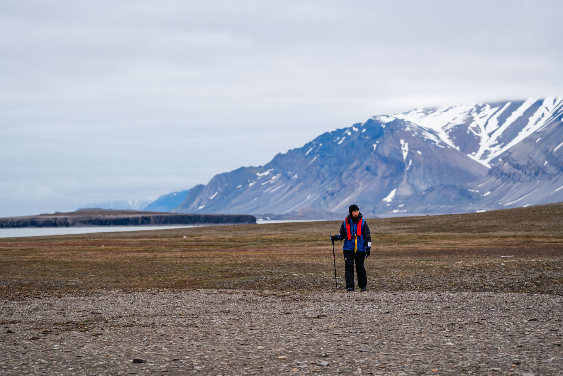 Woman hiking across rocky landscape, Belsund, Svalbard, Lina Stock