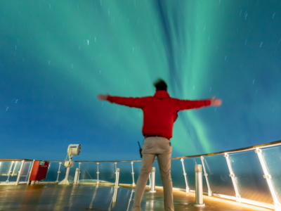 Passenger marvelling at the Northern Lights from the deck of the Greg Mortimer ship in Greenland